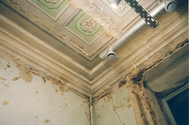 Water-stained ceiling and wall with peeling paint